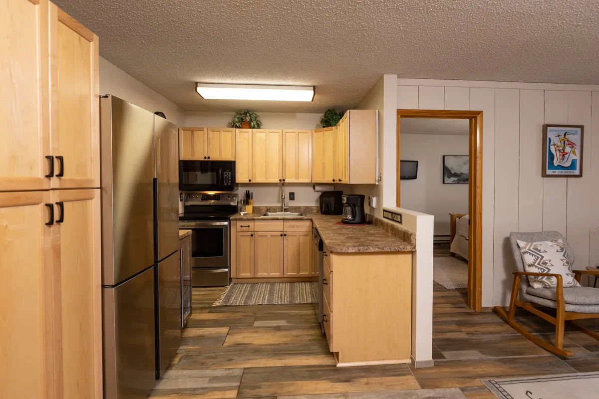 A warm, functional kitchen with stainless steel appliances and spacious countertops, designed for group cooking and gatherings. The space exudes both coziness and practicality, perfect for preparing meals and enjoying each other's company.