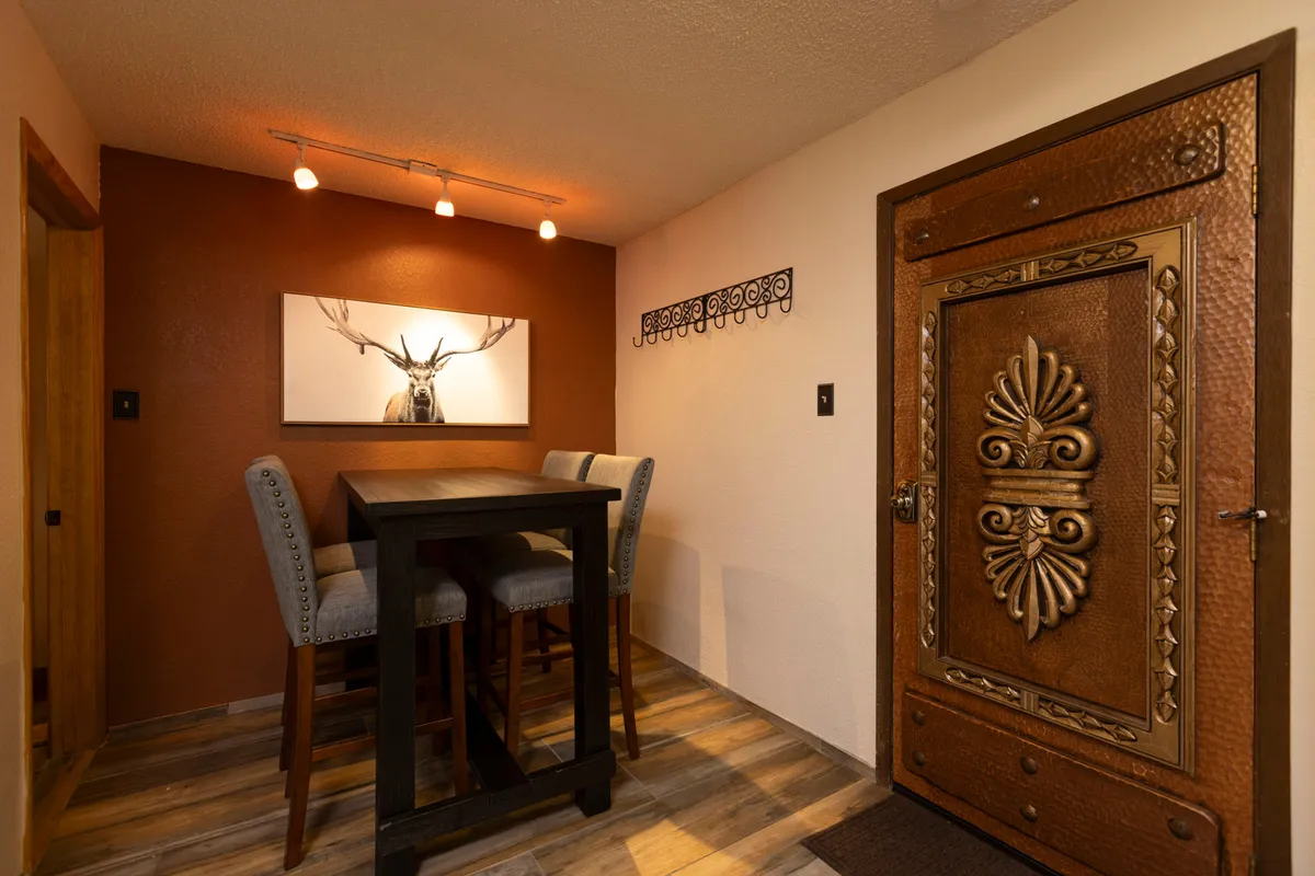 A stylish indoor dining area featuring a decorative door, high-top table, and artwork. The ambiance is intimate and welcoming, ideal for casual dining, drinks, and conversations after a day outdoors.