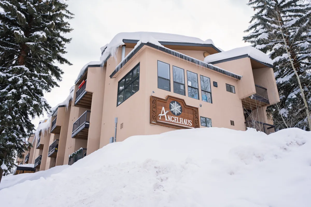 An inviting exterior view of the Angel Haus building with its sign prominently displayed, nestled in a pristine, snow-covered landscape under bright winter skies.