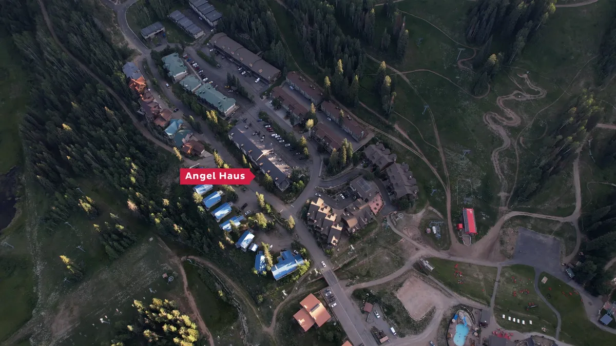 An exterior shot of Angel Haus and nearby buildings nestled into the natural landscape. The scene features soft sunset lighting and hints at cozy evenings, reinforcing the sense of resort community and access to multiple amenities.